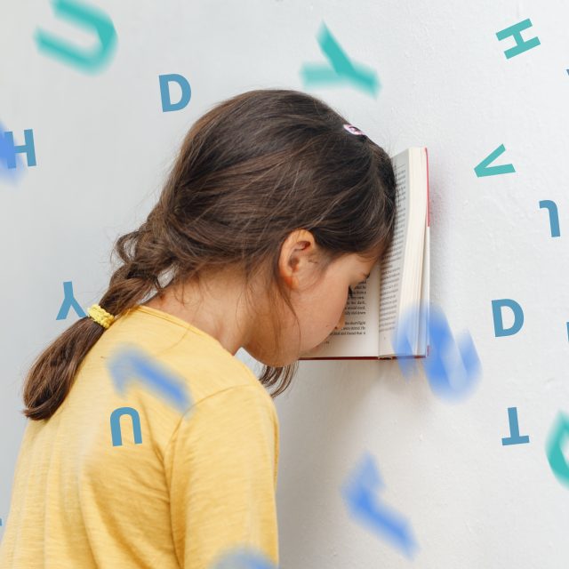 Sad and tired caucasian girl with dyslexia holds a book on her forehead. Flying tangled letters in the air. The child learns to speak and read correctly